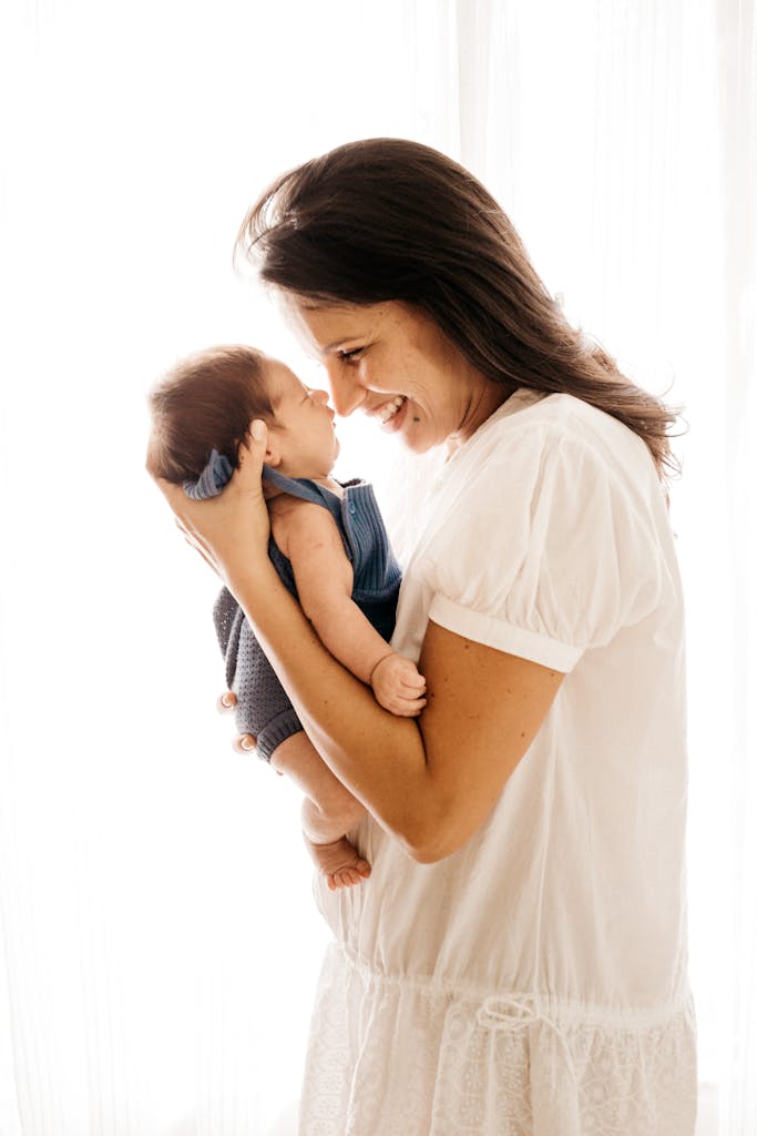 A joyful mother cradles her infant closely, expressing love and happiness.