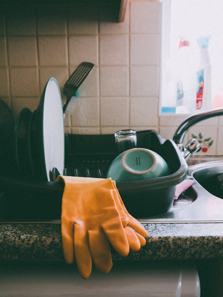 Cozy kitchen setup featuring a dish rack, dishes, and yellow gloves, ideal for a homey atmosphere.